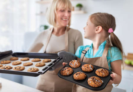 Happy senior granny and her granddaughter showing cookiesの写真素材