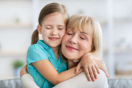 Happy mature woman and granddaughter hugging, closeupの写真素材