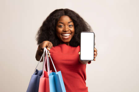 Online Shopping App. Cheerful african american woman demonstrating smartphone with white screen