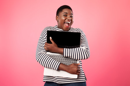 Joyful Overweight African American Lady Hugging Laptop Computer, Pink Backgroundの写真素材