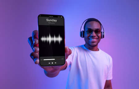 Music App. Black Guy In Headphones Showing Smartphone With Audio Player Interfaceの写真素材