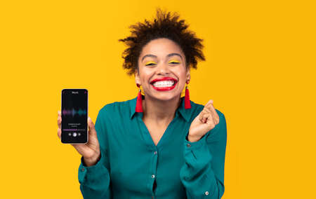 Music Player App. Cheerful African Female Holding Smartphone With Audio Multimedia Galleryの写真素材