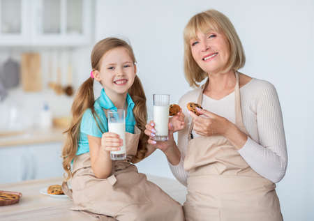 Grandma And Cute Little Girl Eating Cookies Drinking Milkの写真素材