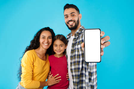 Middle-Eastern Family Showing Cellphone With Empty Screen Over Blue Backgroundの写真素材
