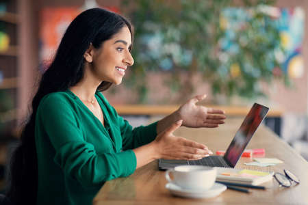 Long-haired indian lady having online job interview, cafe interiorの写真素材