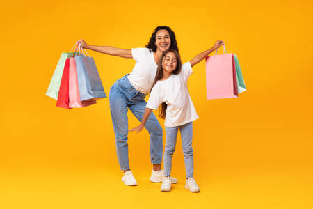 Arab Mother And Daughter Shopping Holding Shopper Bags, Yellow Backgroundの写真素材