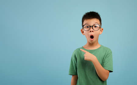Amazing Offer. Excited Asian Boy Wearing Eyeglasses Pointing Aside At Copy Spaceの写真素材