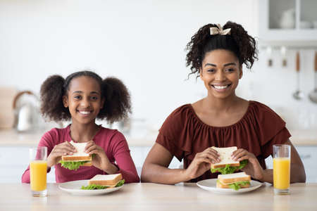 Cheerful african american mother and daughter havign healthy lunchの写真素材