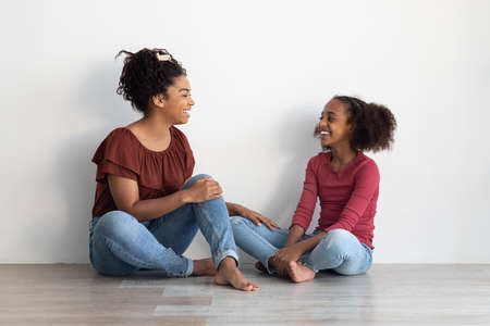 Cheerful black mom and kid chatting at homeの写真素材