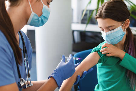 Teen Girl Receiving Vaccine Injection In Arm In Medical Centre
