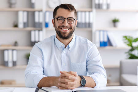 Portrait of cheerful mature caucasian male in glasses working at laptop, calling onlineの写真素材