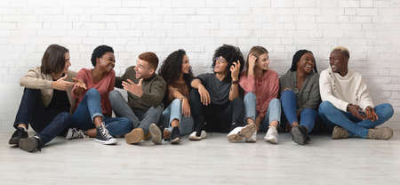 Carefree multiracial group of friends chilling together on floorの写真素材