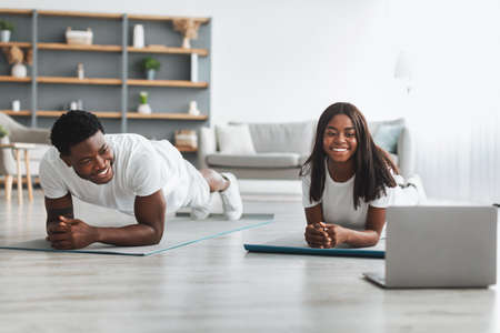 Young black couple planking in front of laptop