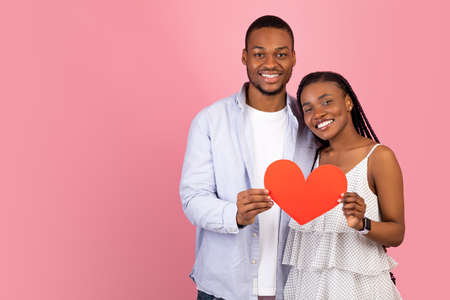 Young Romantic Black Couple Hugging And Holding Red Paper Heart