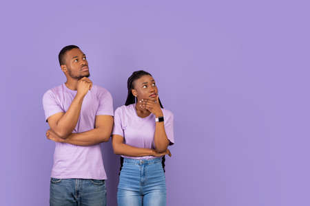 Pensive black couple looking aside at free copy space, thinking