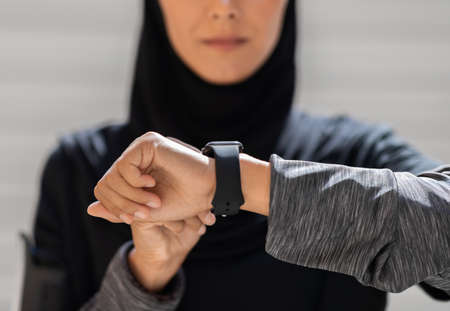 Sport Gadgets Concept. Muslim Woman In Hijab Checking Fitness Activity On Smartwatch