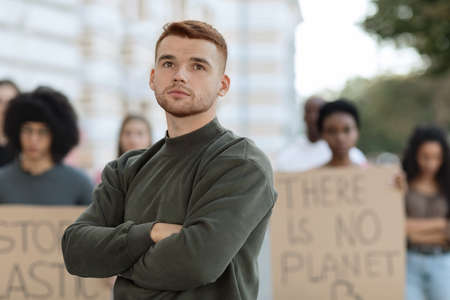 Thoughtful young man posing over multiracial group of demonstratorsの写真素材