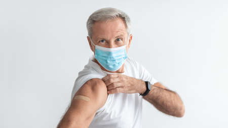Vaccinated Senior Male Wearing Face Mask Showing Arm, Gray Backgroundの写真素材
