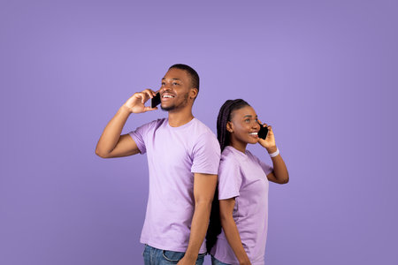 African american couple talking on smartphones, violet studio wall