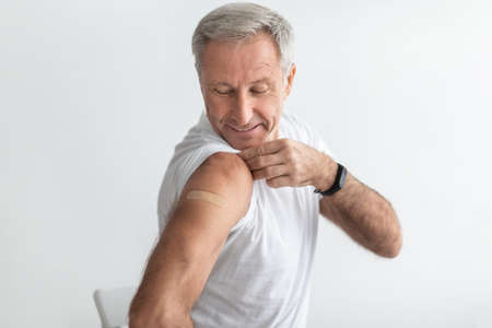 Mature Man Posing After Coronavirus Vaccination Showing Arm, Gray Backgroundの写真素材