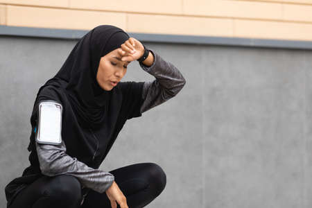 Tired Sporty Muslim Woman Taking Breath After Active Training Outdoorsの写真素材