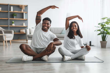 Young black couple doing side bend exercise together