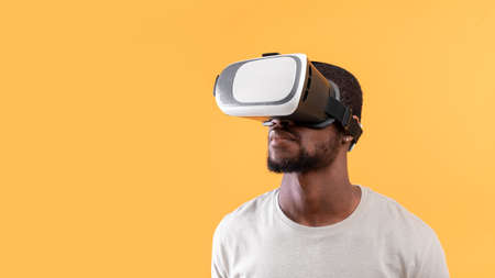Modern technologies for entertainment. Young black guy wearing vr glasses, experiencing virtual reality, free spaceの写真素材