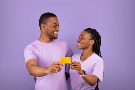 Happy black couple hugging and holding credit card