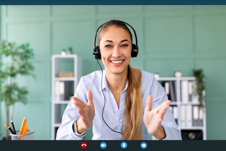 Remote work and technology. Happy woman wearing headphones while having video conferenceの写真素材