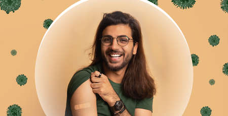 Smiling arabian millennial guy showing shoulder with bandage after vaccination on beige background