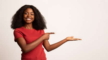 Check This. Cheerful Young Black Lady Pointing At Her Open Empty Palmの写真素材