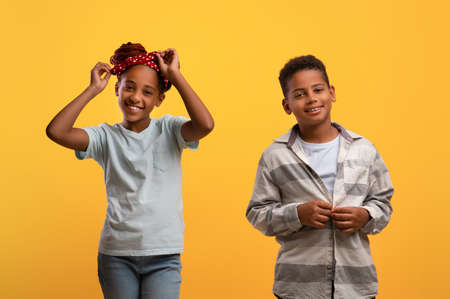 Stylish african american kids posing on yellow studio background