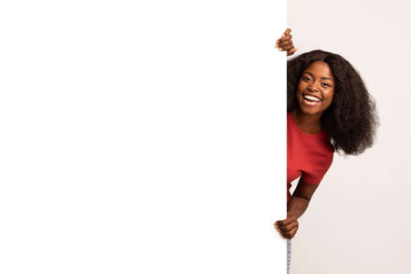 Joyful Young Black Lady Standing Behind Big White Advertisement Boardの写真素材