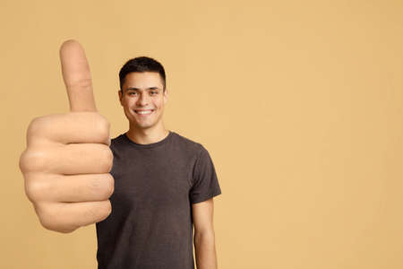 Cheerful guy showing thumb up, big gestures conceptの写真素材