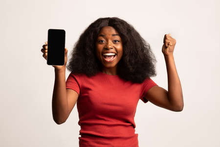 Big Luck. Overjoyed African American Lady Holding Blank Smartphone And Celebrating Successの写真素材