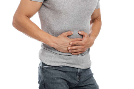 Cropped millennial european male suffering from abdominal pain and pressing his hands to sore spotの写真素材