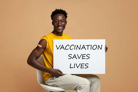 African American Guy Advertising Vaccination, Holding Motivational Placard And Smiling At Cameraの写真素材