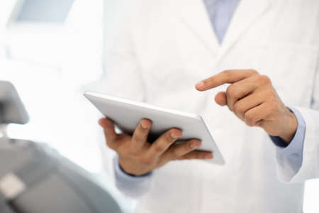 Modern Technologies And Dentistry. Male Dentist Using Digital Tablet In Clinic, Closeupの写真素材