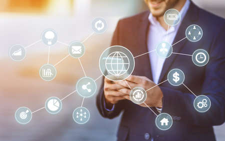 Successful handsome young european guy in suit checks financial app on phone, double exposure with...