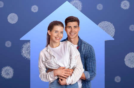 Beautiful young couple standing inside house shape frame and hugging