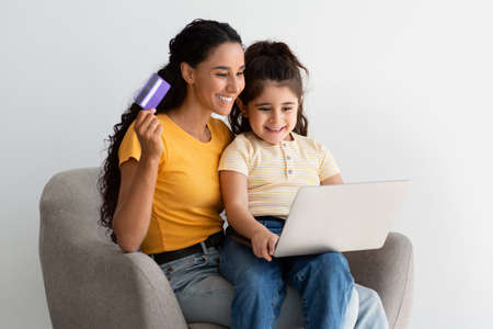 Happy Mom And Little Daughter Shopping Online With Laptop And Credit Cardの写真素材