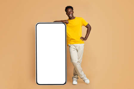 Cool App. Cheerufl Black Male Leaning At Big Smartphone With White Screenの写真素材