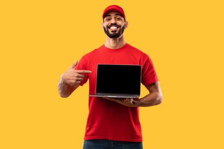 Delivery Guy Showing Laptop Screen Advertising Website Over Yellow Backgroundの写真素材