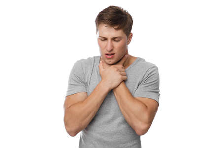 Despaired millennial european handsome guy presses his hands to throat and suffocates, isolated on white backgroundの写真素材