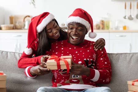 Loving black lady greeting her boyfriend, celebrating Christmasの写真素材