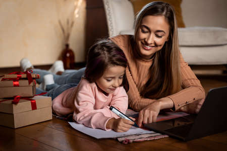 Portrait of cute girl writing letter to Santa with momの写真素材