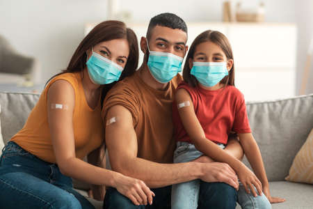 Arab Family In Masks Showing Adhesive Bandage After Receiving Injectionの写真素材