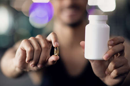 Sports Multivitamins. Athlete Man Holding Blank Jar And Supplement Capsule Pillの写真素材