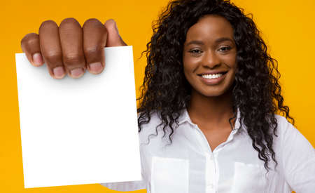 African American Female Holding Blank Card Standing Over Yellow Backgroundの写真素材