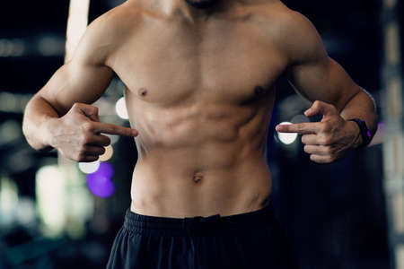 Muscular Young Man With Naked Torso Pointing At Sick-Pack Abs Musclesの写真素材